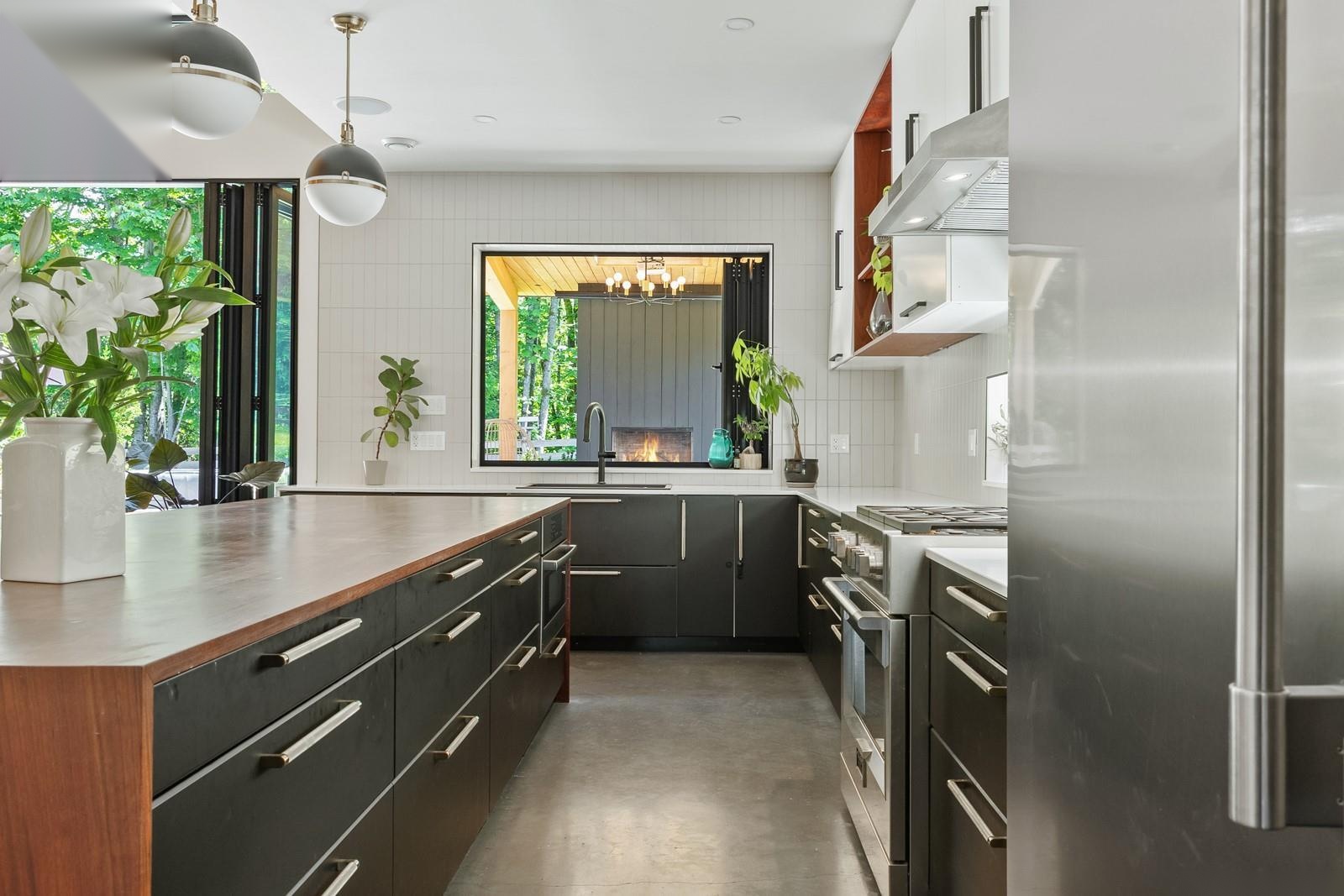 Modern kitchen with dark cabinetry, hardwood island, and premium appliances